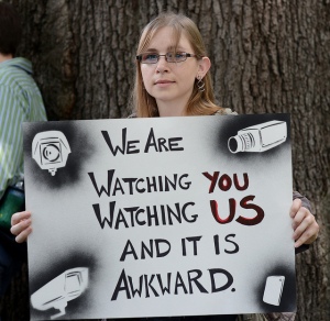 Woman holding a sign: We are watching you watching us and it is awkward.